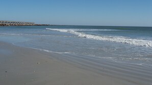 A beach with a pier extending into the water. - Beachfront 2-bedroom condo with breathtaking ocean views from every room! (Fernandina Beach)
