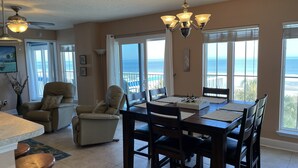 A dining area with a view of the ocean, a ceiling fan, and a chandelier. - Beachfront 2-bedroom condo with breathtaking ocean views from every room! (Fernandina Beach)