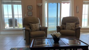 A living room with two leather armchairs, a glass coffee table, and a colorful rug. - Beachfront 2-bedroom condo with breathtaking ocean views from every room! (Fernandina Beach)