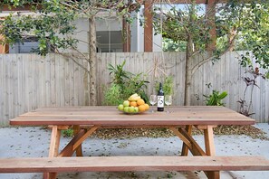 Ein Holztisch für ein Picknick mit einer Obstschale und Weingläsern.