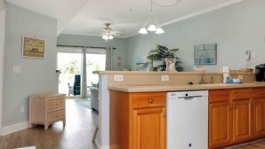 Une cuisine avec des meubles en bois, un lave-vaisselle blanc et un ventilateur de plafond.