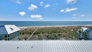 Une vue sur la côte, avec une plage, un bâtiment doté d’un toit bleu et un ciel dégagé.