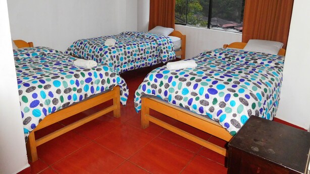 Quarto com duas camas, cada uma com colcha de bolinhas, cabeceiras de madeira e uma janela com cortinas.
