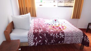 Quarto com cama, uma cadeira de madeira e janela com cortinas.