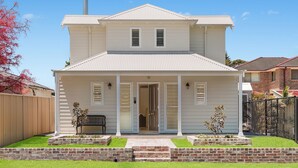 A two-story house with a front porch, a garage, and a fenced backyard. - Little Lewis - Romantic Getaway (Callala Beach)