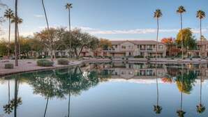 A hotel with a reflective pool, palm trees, and a clear sky. - Superstition Lakes Condo, A+ Golf View, Comm Htd POOL & SPA; Walk to Mall & Theater (Mesa)
