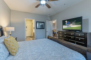 A bedroom with a bed, a television displaying a golf game, a ceiling fan, and a dresser. - Superstition Lakes Condo, A+ Golf View, Comm Htd POOL & SPA; Walk to Mall & Theater (Mesa)