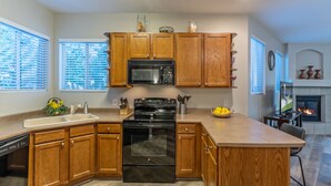 A modern kitchen with wooden cabinets, a black stove, a microwave, and a dishwasher. - Superstition Lakes Condo, A+ Golf View, Comm Htd POOL & SPA; Walk to Mall & Theater (Mesa)