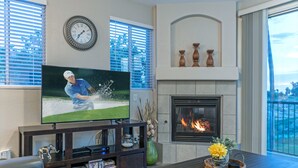 A living room with a flat-screen TV, fireplace, and large windows. - Superstition Lakes Condo, A+ Golf View, Comm Htd POOL & SPA; Walk to Mall & Theater (Mesa)