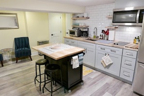 Una cocina compacta con una isla central, microondas, cafetera y lavaplatos.