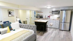 Ein modernes Hotelzimmer mit Bett, einer kleinen Küchenzeile und einem Esstisch.
