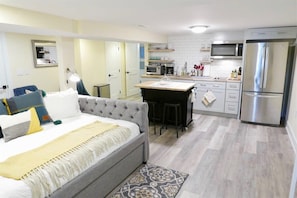 Una habitación de hotel moderna con una cama grande, una kitchenette y un comedor.