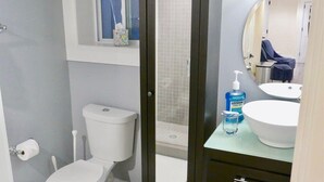 Ein Badezimmer mit Toilette, Bidet und Badewanne. Über dem Waschbecken hängt ein Spiegel, über der Toilette ein Fenster.