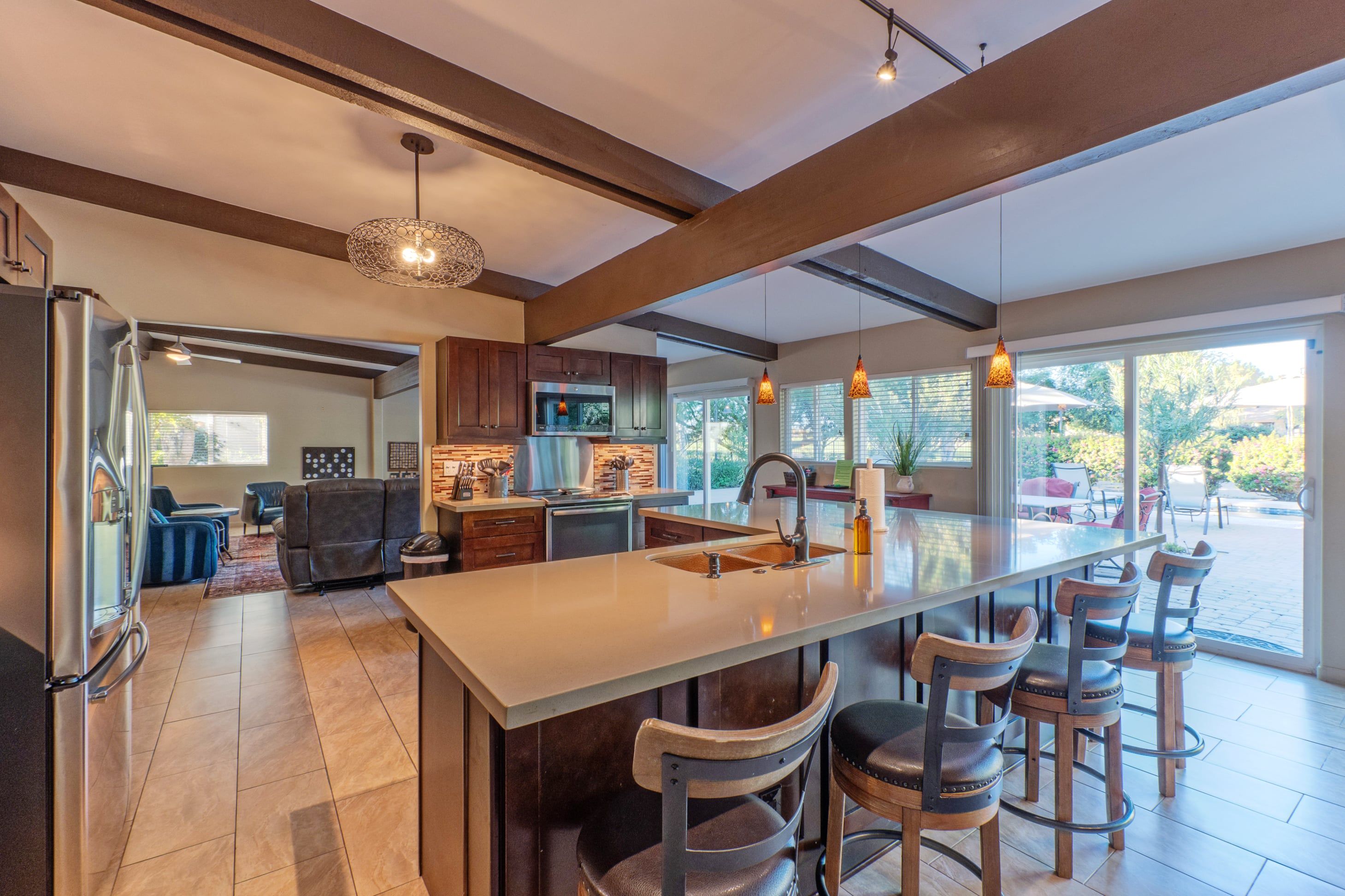 A modern kitchen with a large island, bar stools, and a dining area with a view.