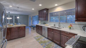 A modern kitchen with wooden cabinets, a stainless steel refrigerator, and a large window with blinds. - Starfire GOLF VIEW, Heated POOL, TVs All BRs, Game Room w/Pool Table (Scottsdale)