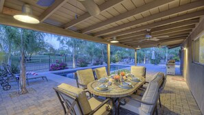 An outdoor patio with a pool, dining table, and chairs, surrounded by a fence and trees. - Starfire GOLF VIEW, Heated POOL, TVs All BRs, Game Room w/Pool Table (Scottsdale)