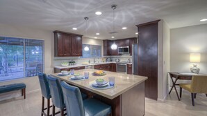 A modern kitchen with a central island, bar stools, a dining table with chairs, and a view of the outdoors through large windows. - Starfire GOLF VIEW, Heated POOL, TVs All BRs, Game Room w/Pool Table (Scottsdale)