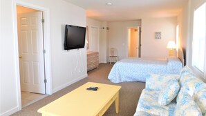 Ein Hotelzimmer mit Bett, einer Couch, einem an der Wand montierten Fernseher und einem kleinen Tisch.