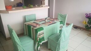 Een eethoek met een tafel bedekt met een gestreepte tafelkleed, omringd door vier gestreepte stoelen.