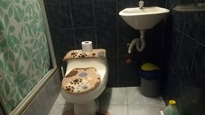 Een badkamer met toilet, wastafel, prullenbak en een badmat.