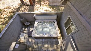 Un bain à remous sur une terrasse en bois, avec une fenêtre sur le côté.