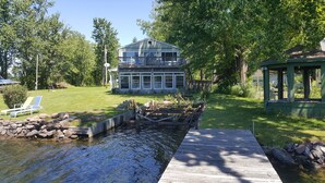 A house with a large deck, a small pond, and a gazebo.