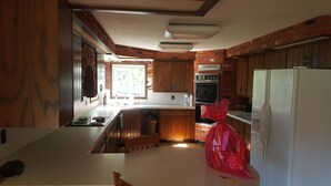 A kitchen with wooden cabinets, a stove, and a refrigerator.