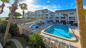 Ein Hotel mit Swimmingpool, Liegestühlen und Palmen.