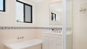 Een moderne badkamer met een bad, een wastafel en een douchehoek.