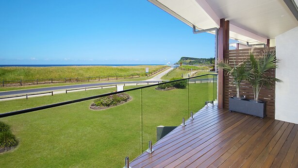 Een balkon met uitzicht op een kustweg en strand.