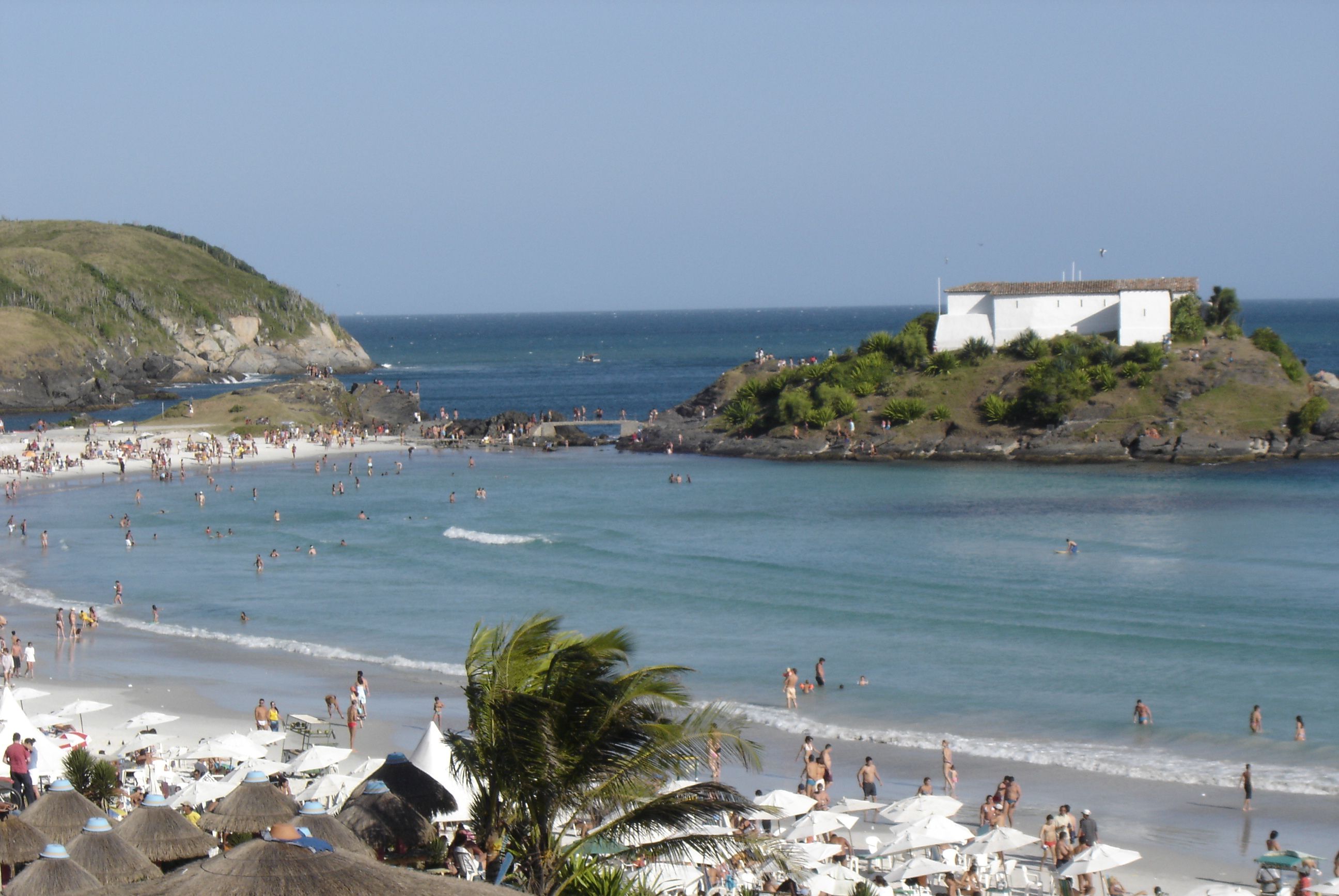 Ein voller Strand mit Sonnenschirmen und Menschen.