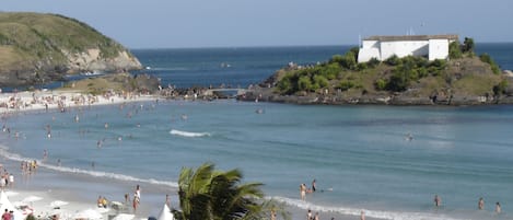 Una playa concurrida con sombrillas y gente.