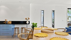 A modern kitchen with a wooden table, stools, and a blue cabinet.