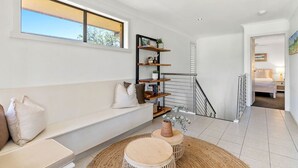 A modern living room with a white sofa, a wooden coffee table, and a staircase leading to another room.