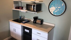 Eine kleine Küche mit Mikrowelle, Toaster und Kaffeemaschine auf der Arbeitsplatte, einem Spülbecken und einem Geschirrspüler.