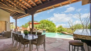 Une terrasse extérieure avec une piscine, une table à manger et des chaises.