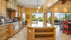 Une cuisine spacieuse dotée de plans de travail en granit, de meubles en bois et d’un grand îlot central.