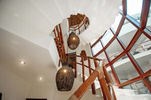 A spiral staircase with wooden railings and a hanging light fixture.