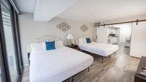 Een hotelkamer met twee bedden, een groot raam en uitzicht op de keuken.