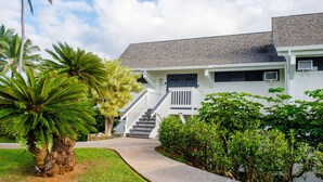 A white two-story house with a grey roof, a front porch, and a staircase leading to the entrance.
