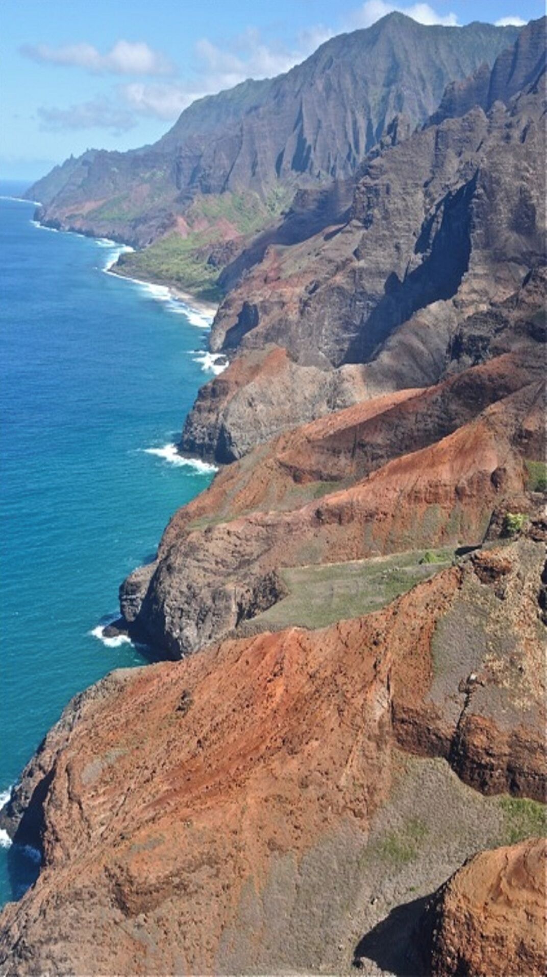 A rugged coastal landscape with steep cliffs and a clear view of the ocean.