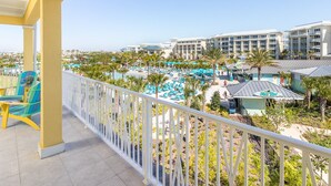 A resort with a pool area, multiple buildings, and a balcony with chairs.