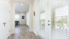 A hallway with wooden flooring, white walls, and a door with a security lock.