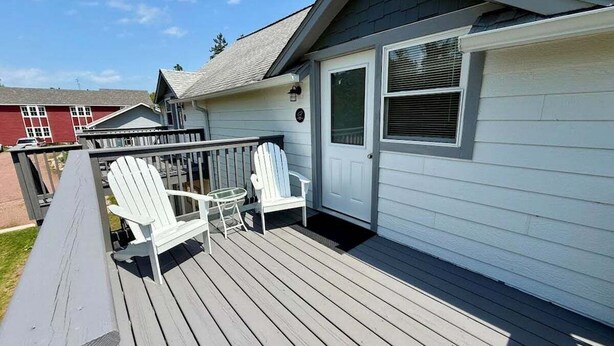 Una terraza con dos sillas Adirondack, una puerta y una ventana.