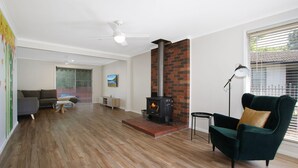 Ein modernes Wohnzimmer mit Kamin, Holzboden und einem grünen Sessel.