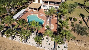 Et toetagers hus med swimmingpool, omgivet af palmer og en anlagt have.