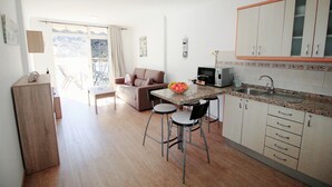 Eine kleine Küche mit Essbereich, einer Couch und Blick ins Freie.