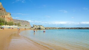 Ein Strand mit klarem Wasser, Felsformationen und ruhiger See.