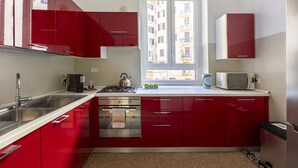 A compact kitchen with red cabinets, a stainless steel sink, a stove, and a microwave. - The bright, spacious apartment is located in Via Luigi Settembrini, on the 1st floor of an elegant Art Nouveau residential building with porter's lodge and elevator, from the early 20th century. During the most recent renovation work, some antique, elegan (Roma)