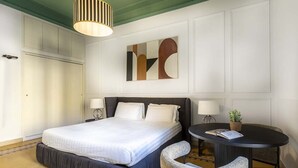 A hotel room with a large bed, two bedside lamps, a round table with a chair, and a modern abstract painting on the wall. - The bright, spacious apartment is located in Via Luigi Settembrini, on the 1st floor of an elegant Art Nouveau residential building with porter's lodge and elevator, from the early 20th century. During the most recent renovation work, some antique, elegan (Roma)